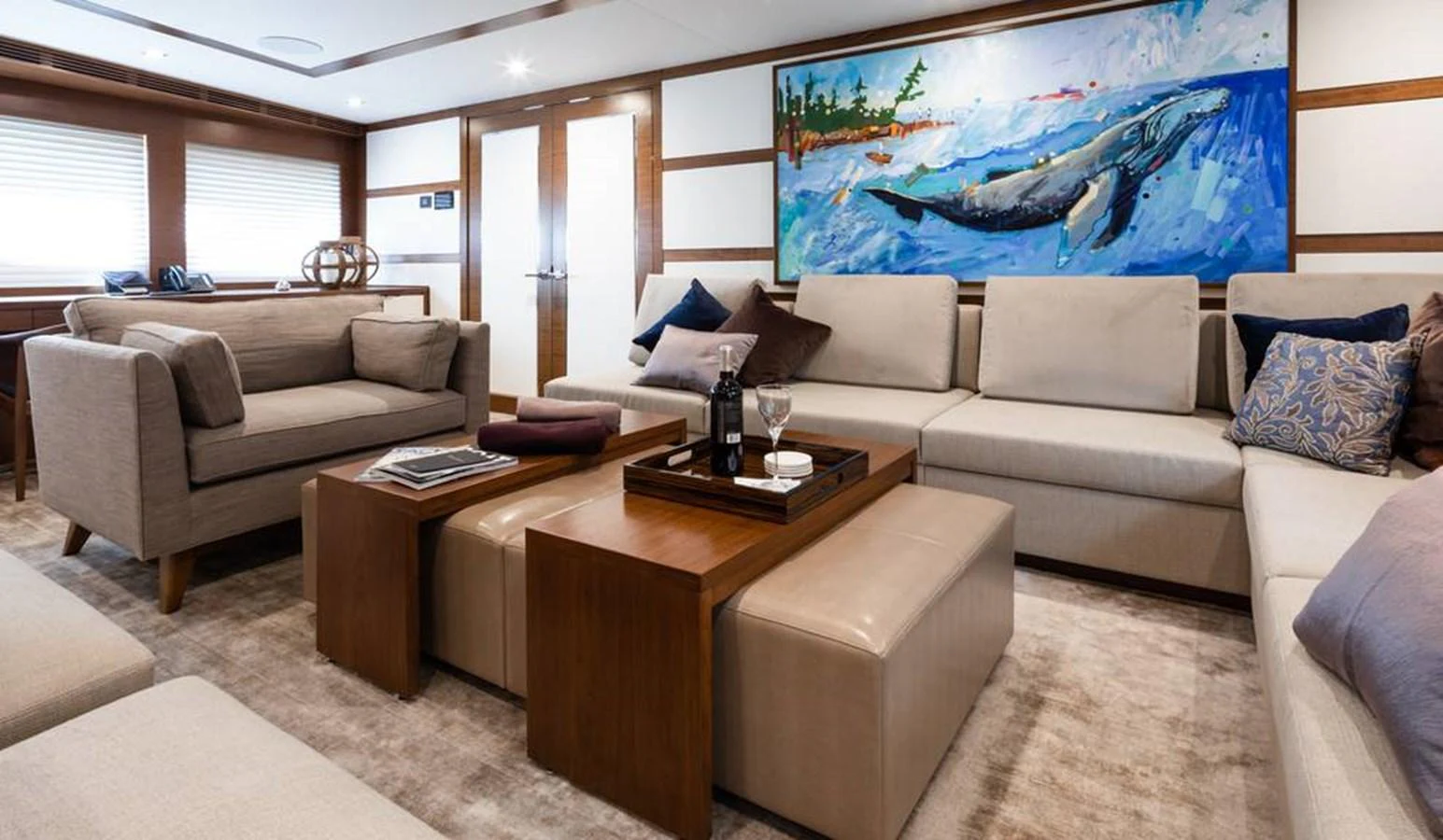 The salon features comfortable seating with a vibrant marine-themed painting as a focal point. aboard NORTHLAND Yacht for Sale