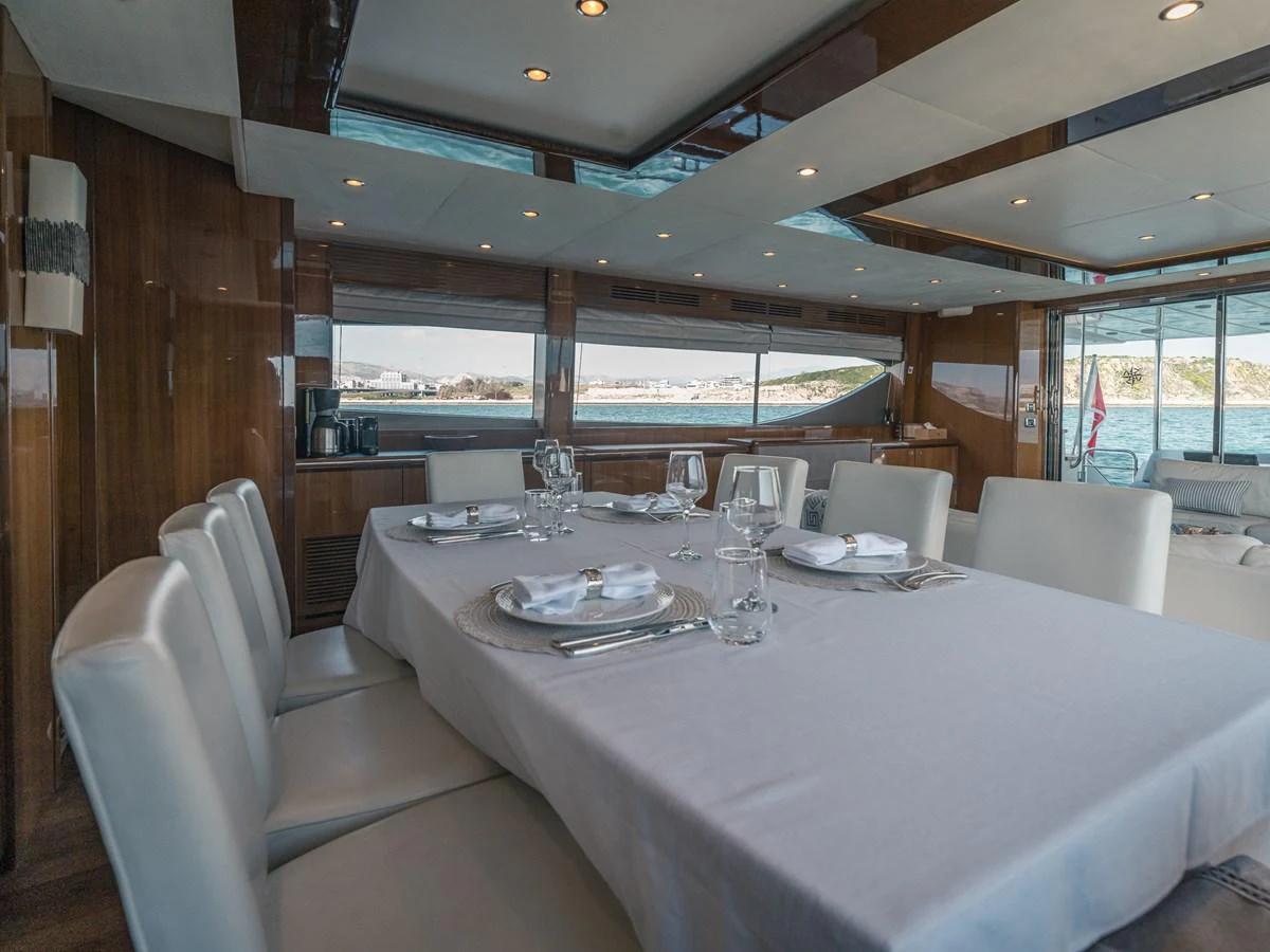 The yacht's dining area features a beautifully set table with a view of the sea through large windows. aboard 4 LIFE Yacht for Sale