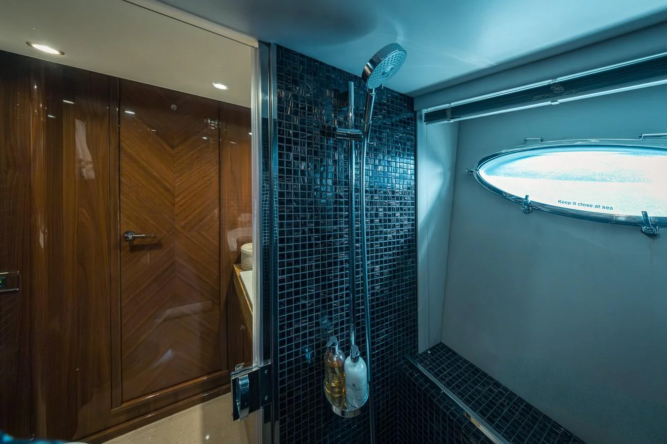 A sleek and modern bathroom with a glass-enclosed shower and a porthole window. aboard 4 LIFE Yacht for Sale