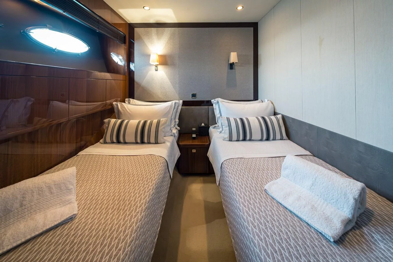 A cozy twin stateroom featuring two single beds with elegant bedding and modern lighting. aboard 4 LIFE Yacht for Sale