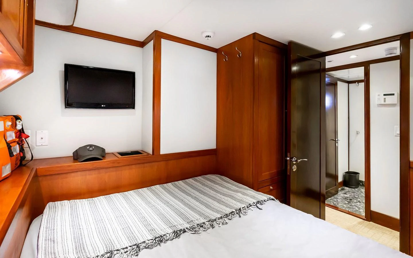A cozy stateroom featuring a comfortable bed, wooden cabinetry, and a mounted television. aboard MISS SARAH J Yacht for Sale