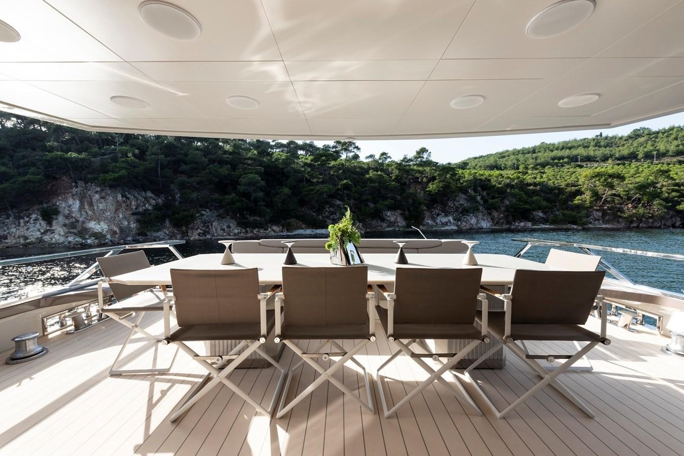 a table and chairs on a balcony overlooking a body of water aboard MAZU 82 Yacht for Sale