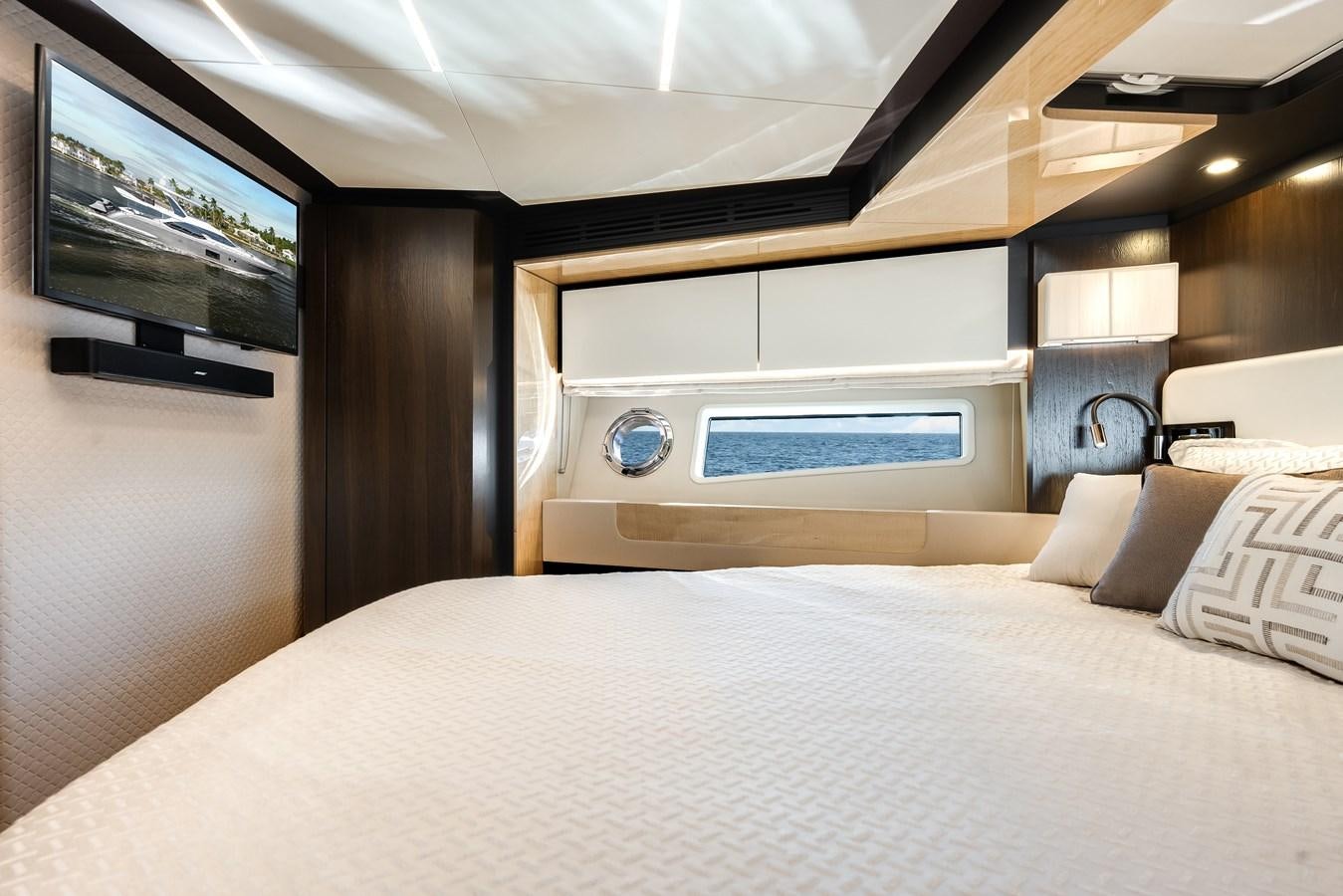 a bed with a white sheet and a television on the wall aboard TRUTH SERUM Yacht for Sale