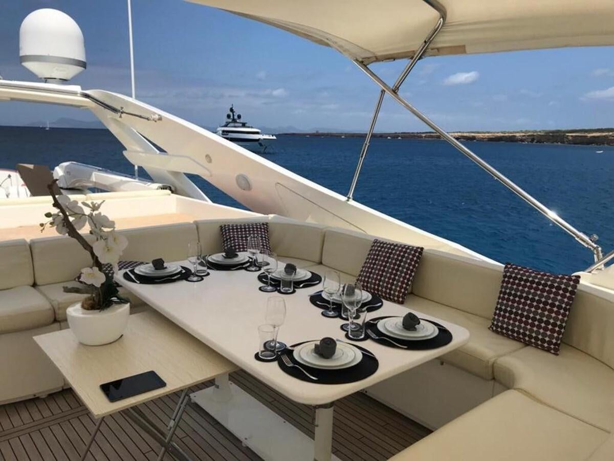 a white table with plates and a laptop on it aboard CAMARIK Yacht for Sale