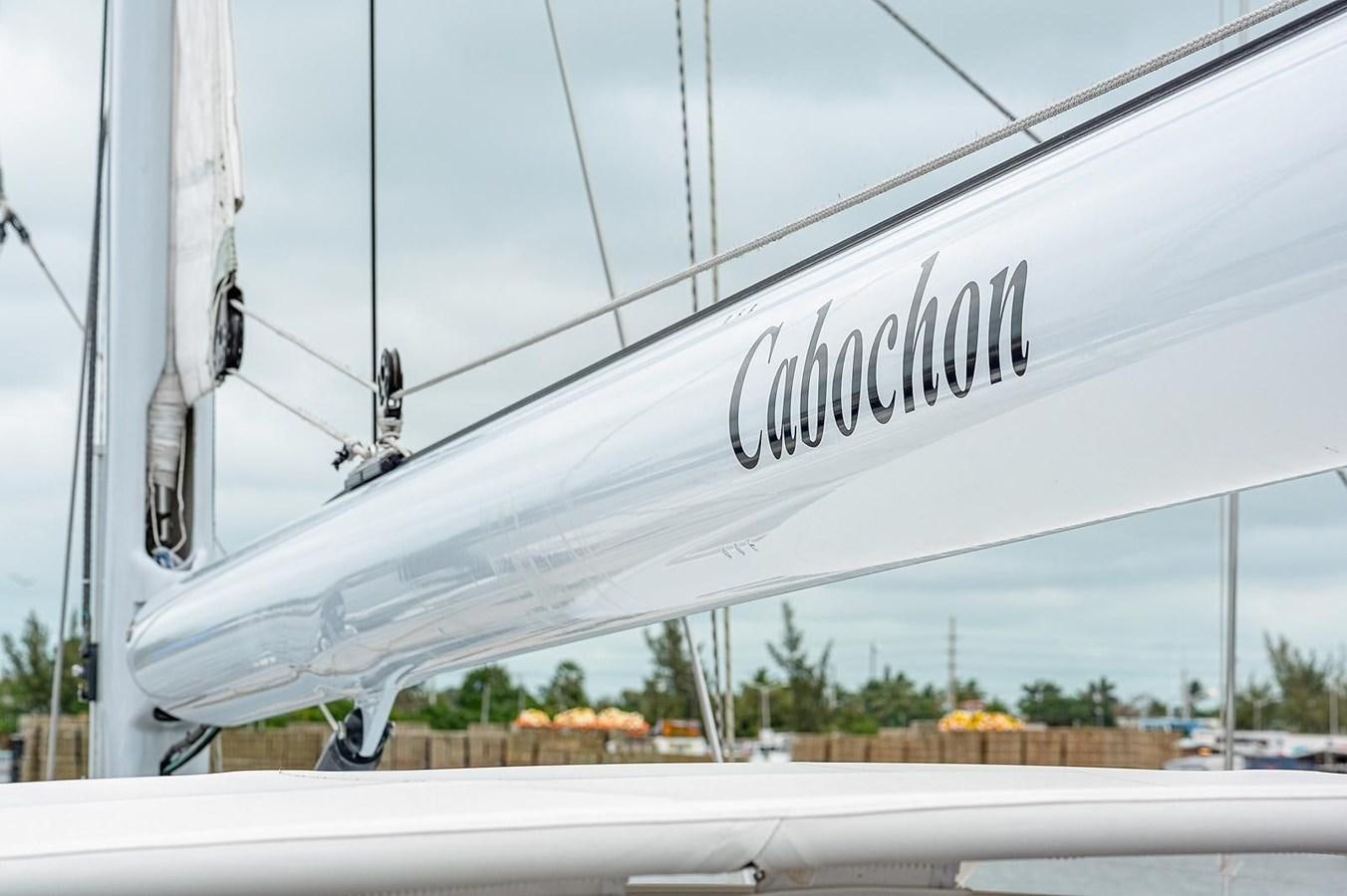 a white boat with a black banner on the front aboard CABOCHON Yacht for Sale