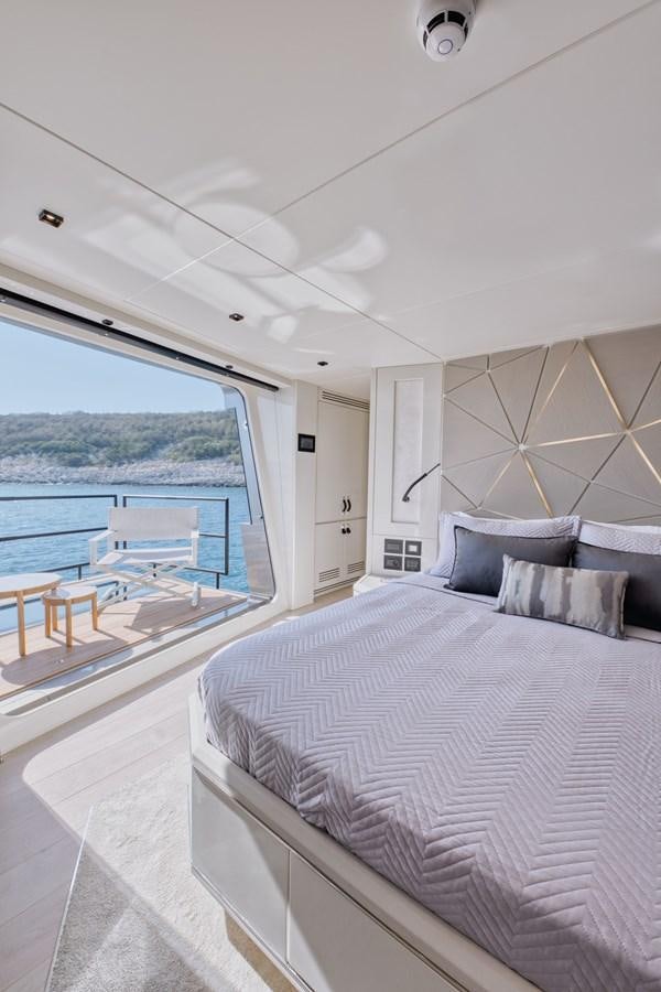 a bed with a large window overlooking a body of water aboard ROCK X Yacht for Sale