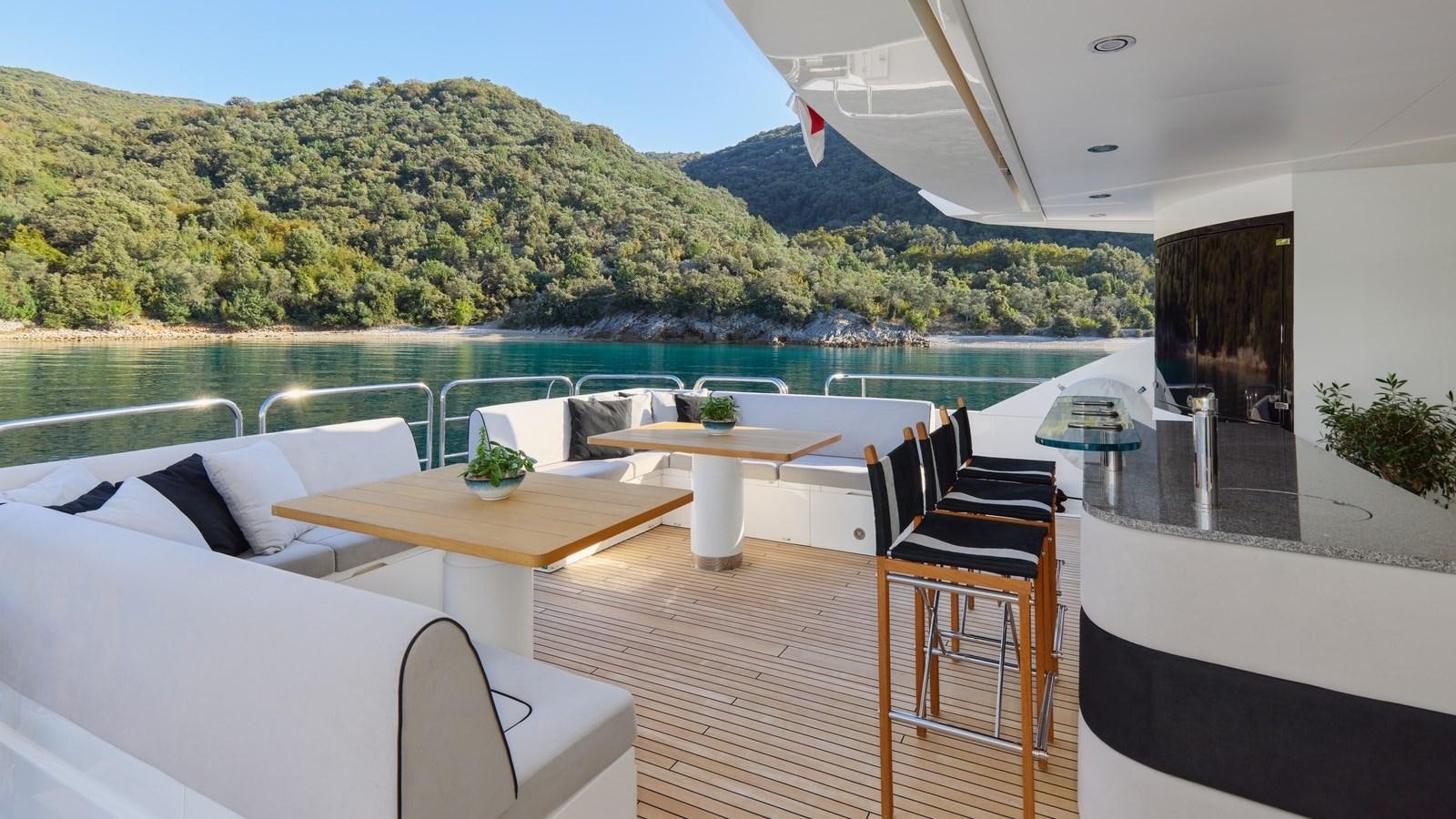 a table and chairs on a deck overlooking a body of water aboard WICKED PLAY Yacht for Sale