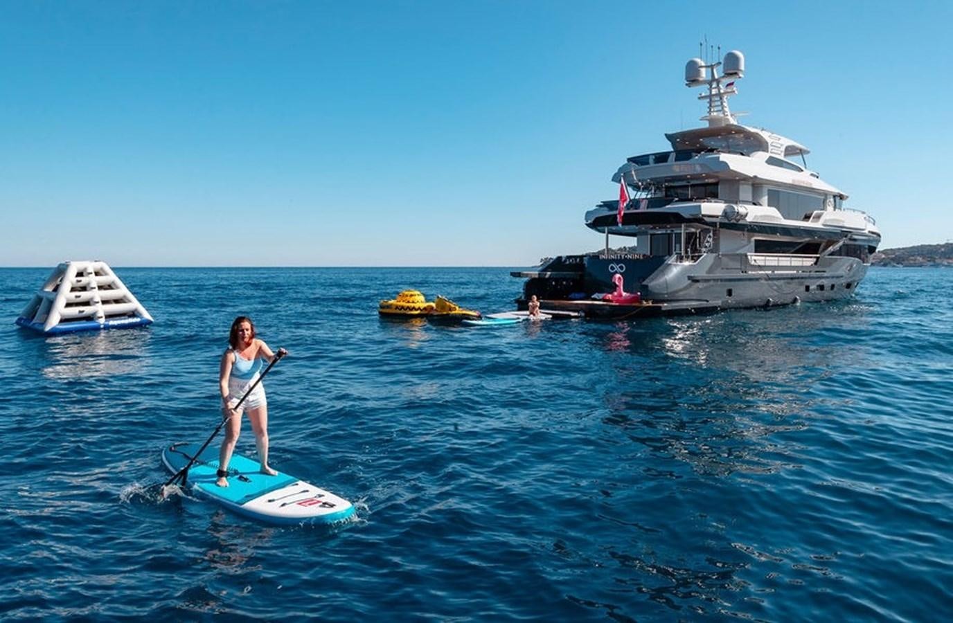 a man paddle boarding with a boat aboard INFINITY NINE Yacht for Sale
