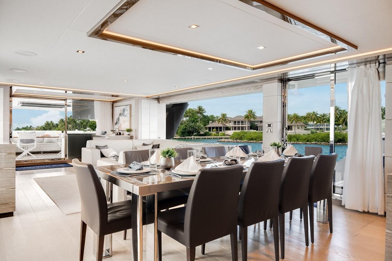 a large dining table with chairs and a large glass window overlooking a city aboard JUST A VACATION Yacht for Sale