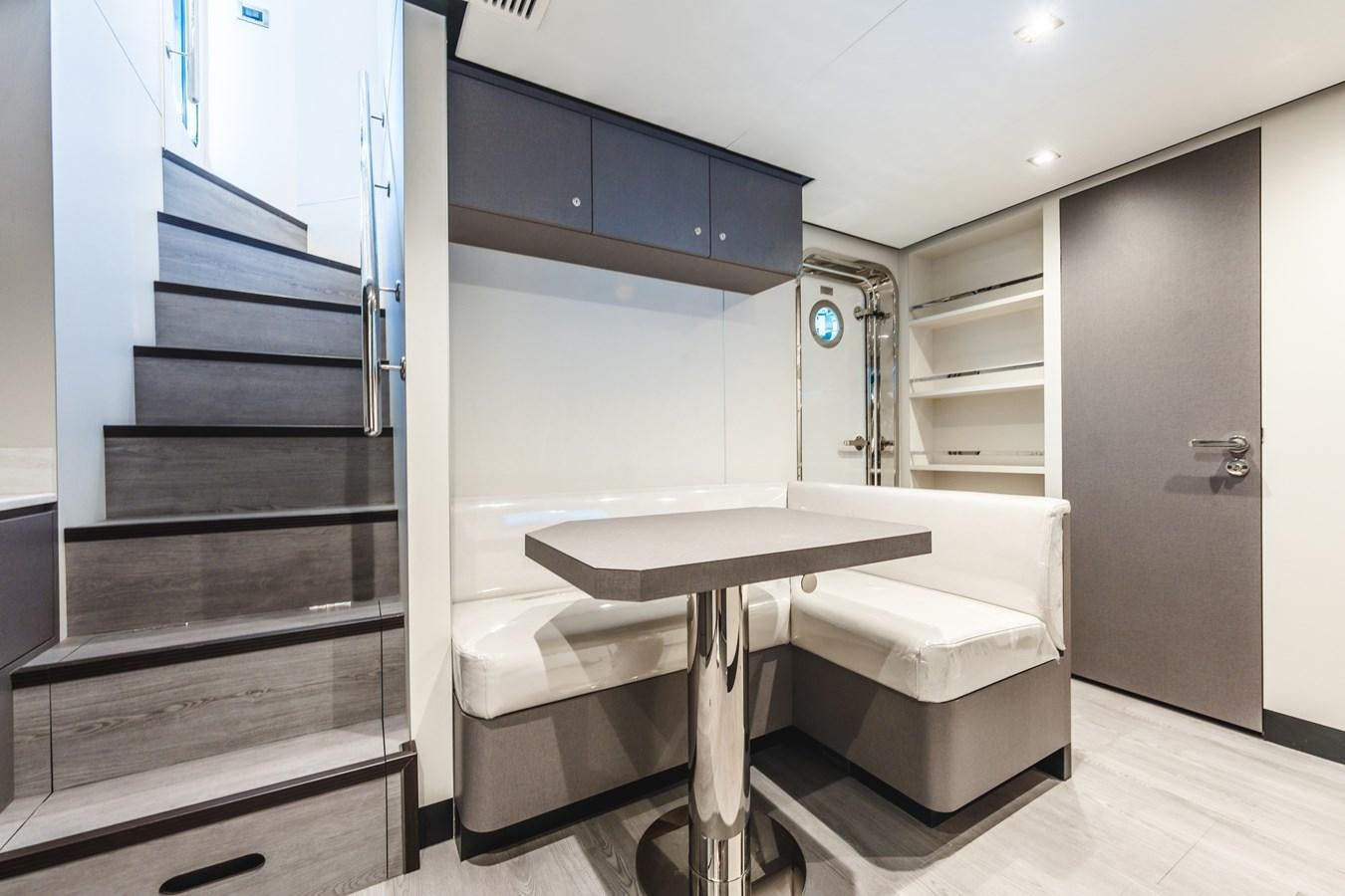 a white rectangular table with a white bench and blue cabinets aboard JUST A VACATION Yacht for Sale