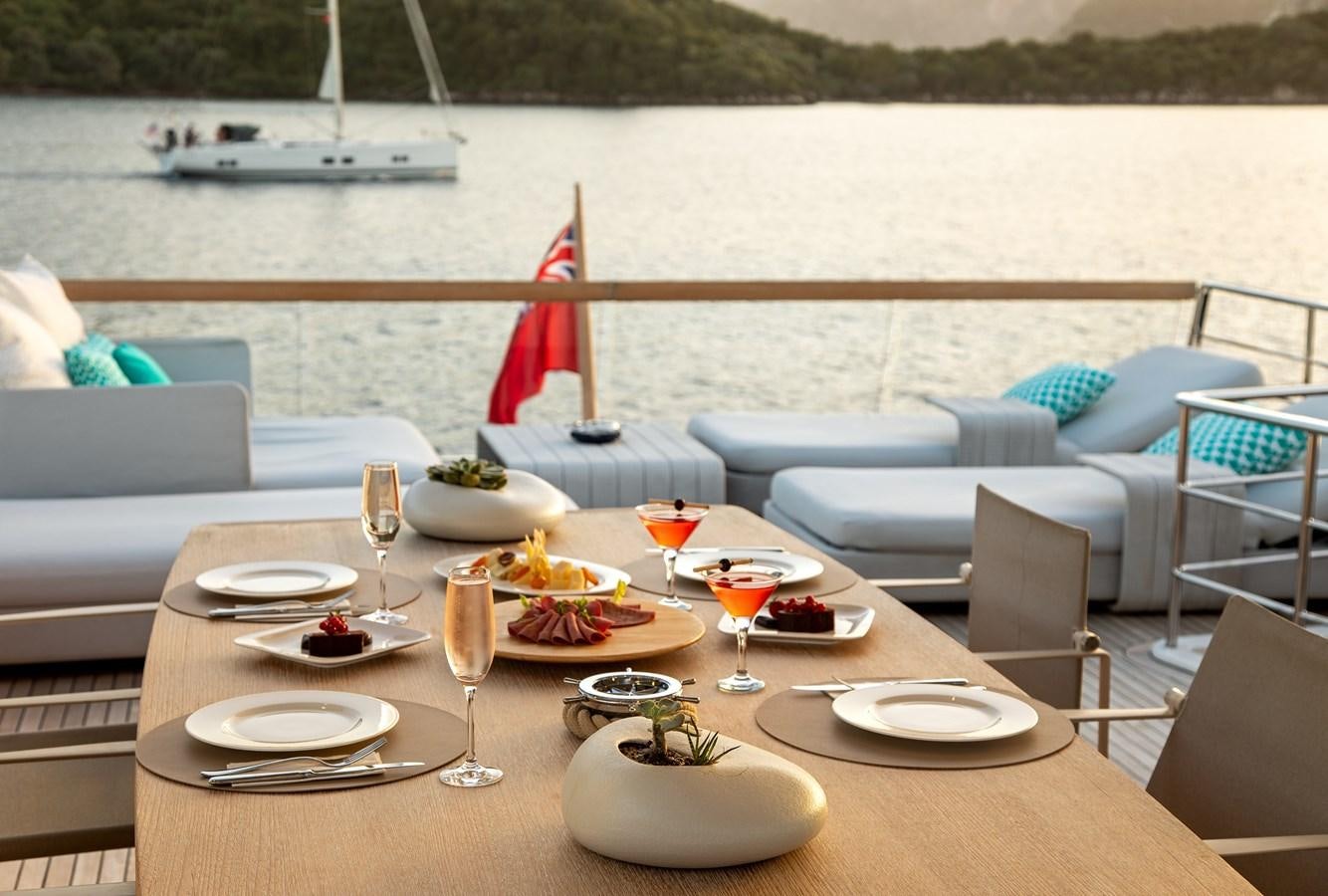 a table set with plates and glasses on a boat in the background aboard CYBELE Yacht for Sale