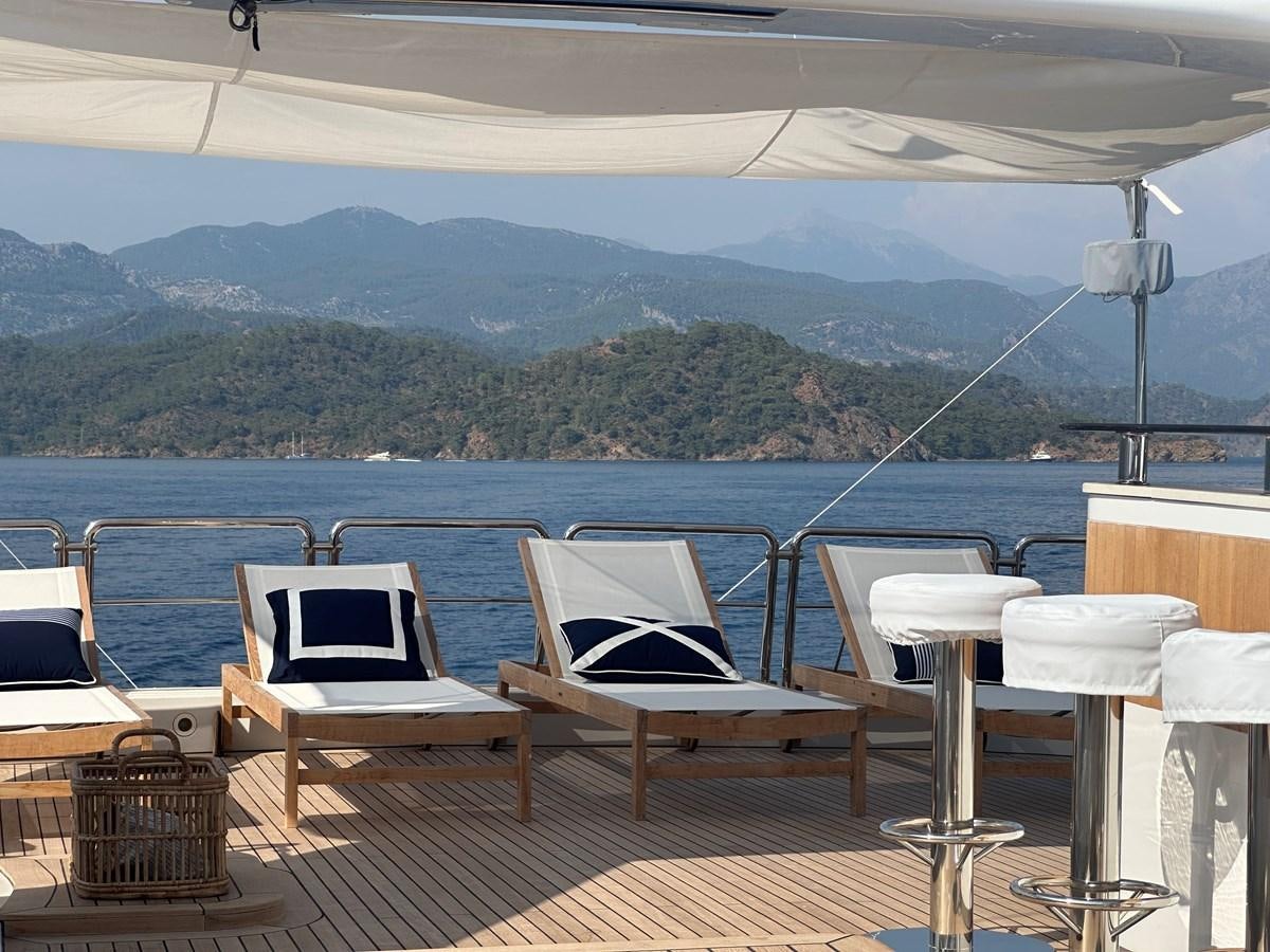 a deck with chairs and tables on it by a body of water aboard FRIENDSHIP Yacht for Sale