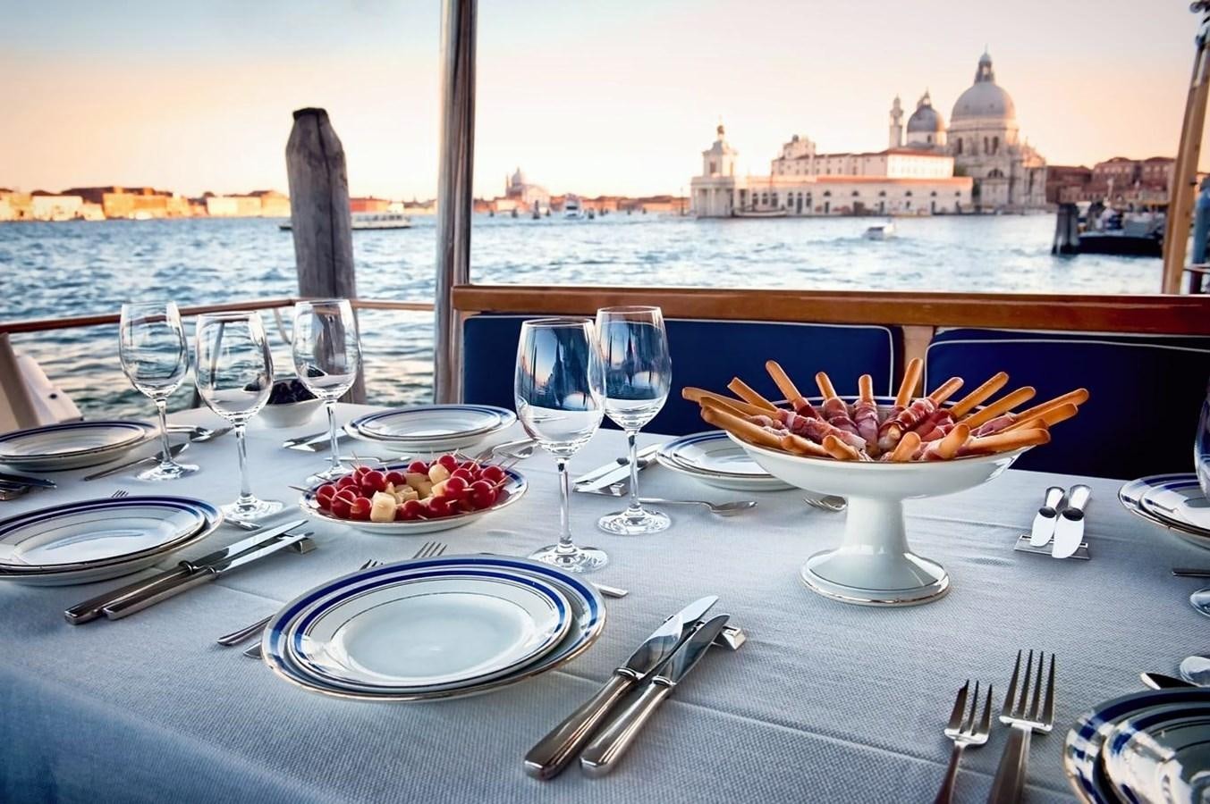 a table with plates and glasses on it aboard LA BOUFFONNE Yacht for Sale