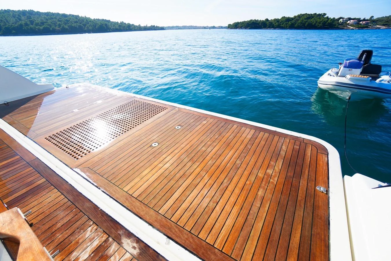 The yacht's aft deck features a spacious and elegant wooden platform with a serene view of the surrounding water. aboard HUBO Yacht for Sale