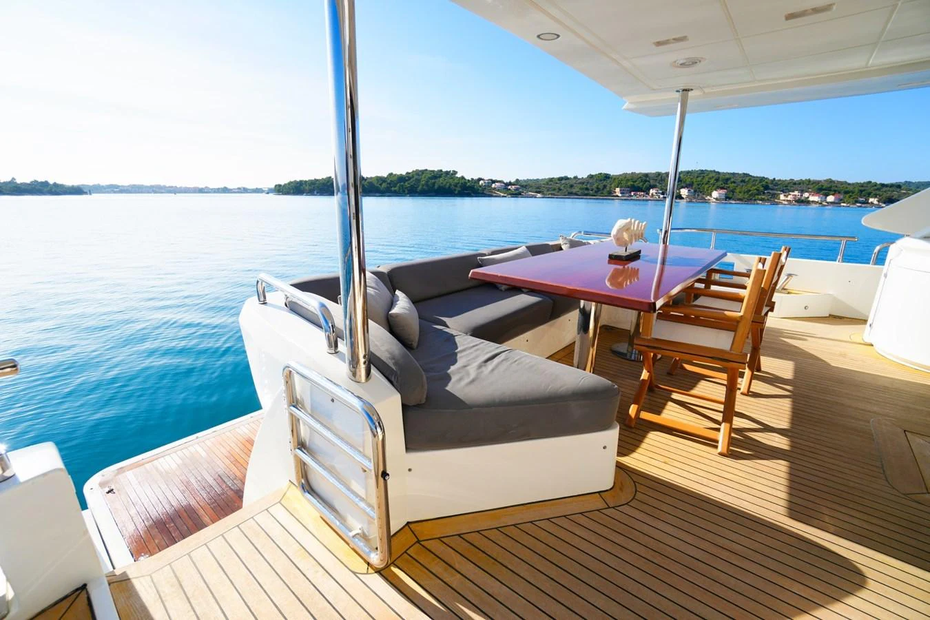 The aft deck features a comfortable seating area with a dining table, perfect for enjoying meals with a view of the serene waters. aboard HUBO Yacht for Sale