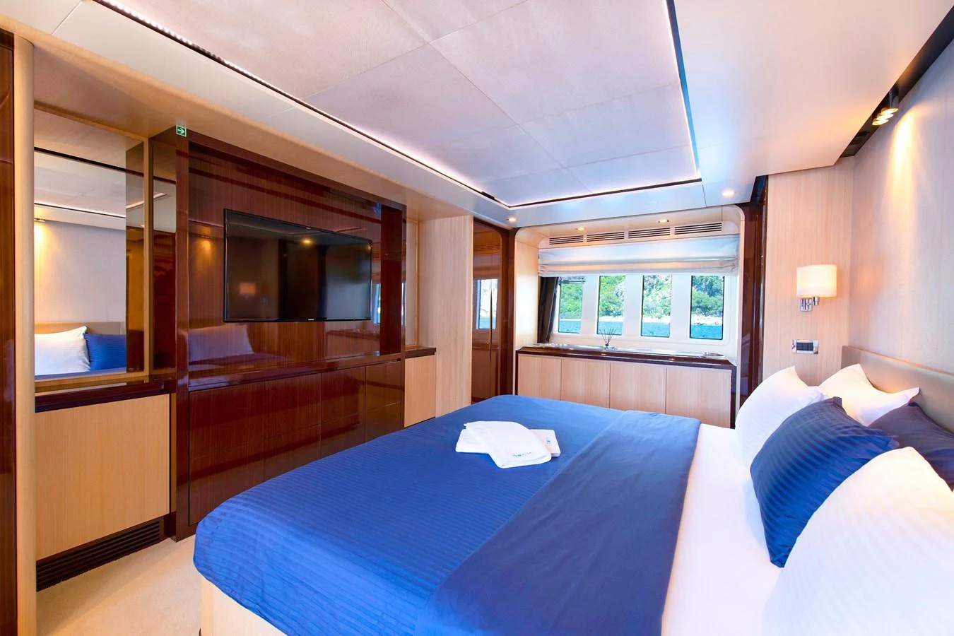 The stateroom features a luxurious bed with elegant bedding and ample natural light from the large windows. aboard HUBO Yacht for Sale