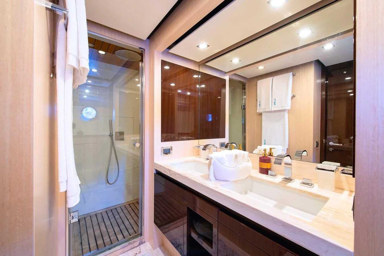 The yacht's bathroom features a spacious shower and a double sink vanity with elegant finishes. aboard HUBO Yacht for Sale