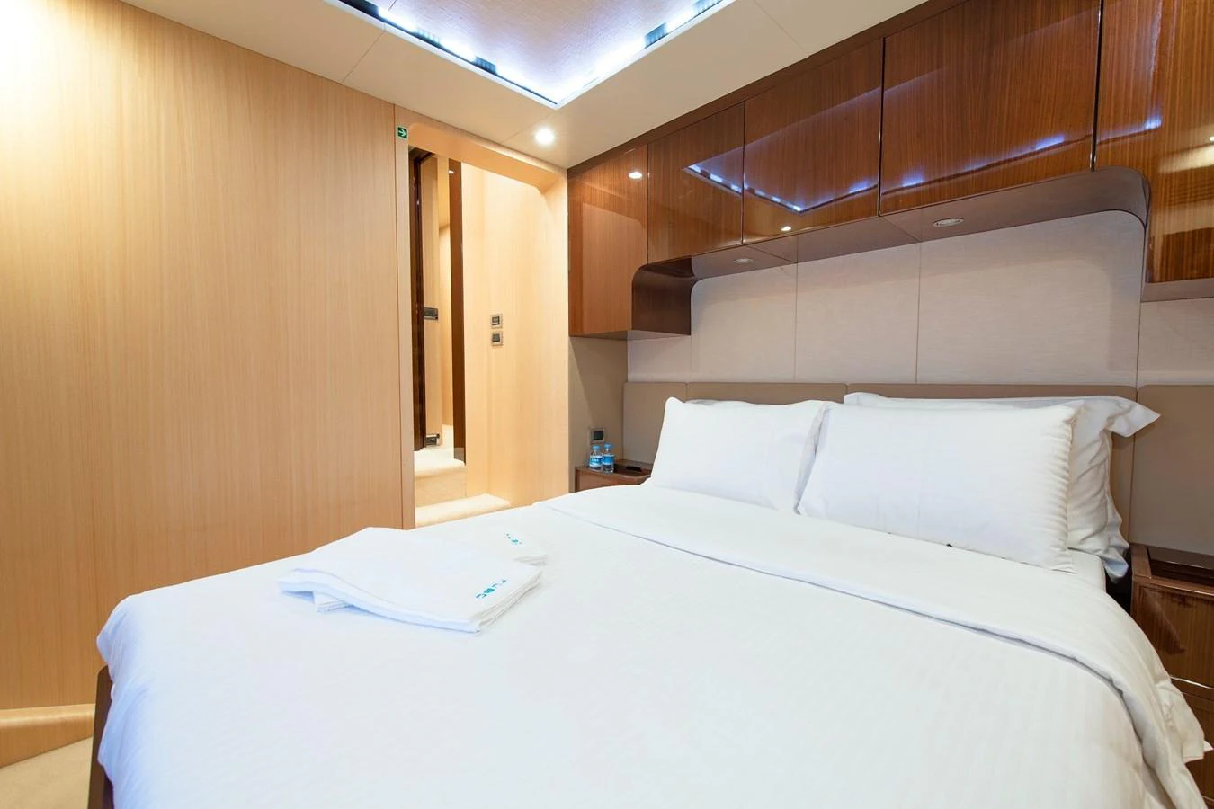 The stateroom features a comfortable bed with crisp white linens and elegant wood paneling. aboard HUBO Yacht for Sale