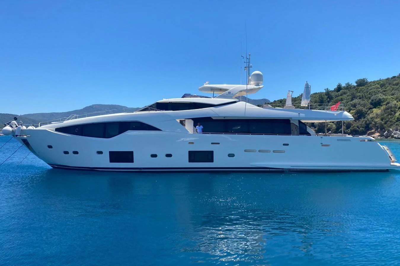 A sleek and modern yacht is anchored in a serene blue bay, showcasing its elegant design and spacious deck areas. aboard HAPPY 2 Yacht for Sale