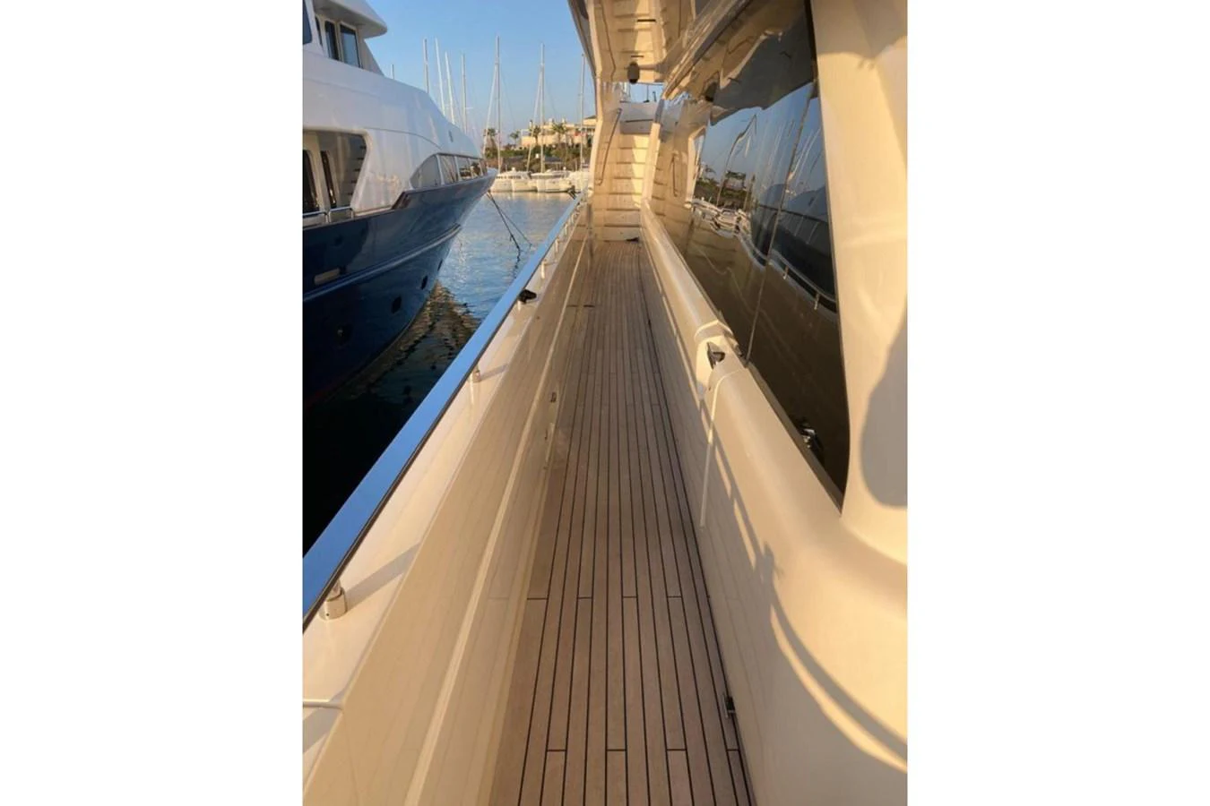 The side deck of the yacht offers a sleek and polished walkway with a view of the marina. aboard HAPPY 2 Yacht for Sale