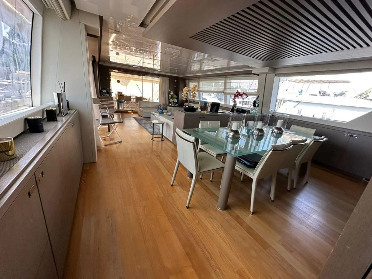 The yacht's dining area features a sleek glass table and modern seating, complemented by ample natural light. aboard HAPPY 2 Yacht for Sale