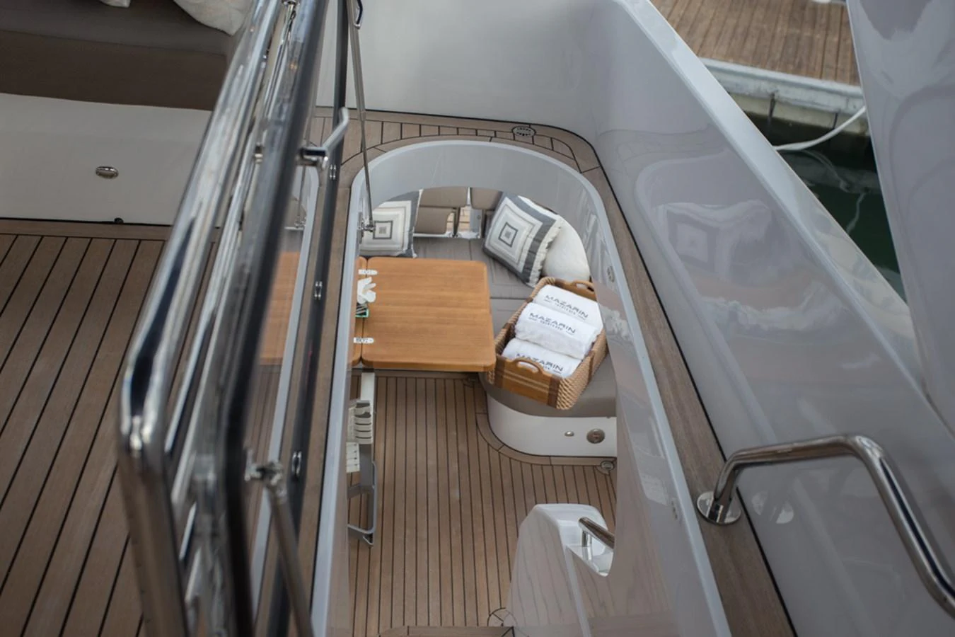 A cozy seating area on the yacht features a wooden table and cushioned seats, perfect for relaxation. aboard MAZARIN 72 FLYBRIDGE Yacht for Sale