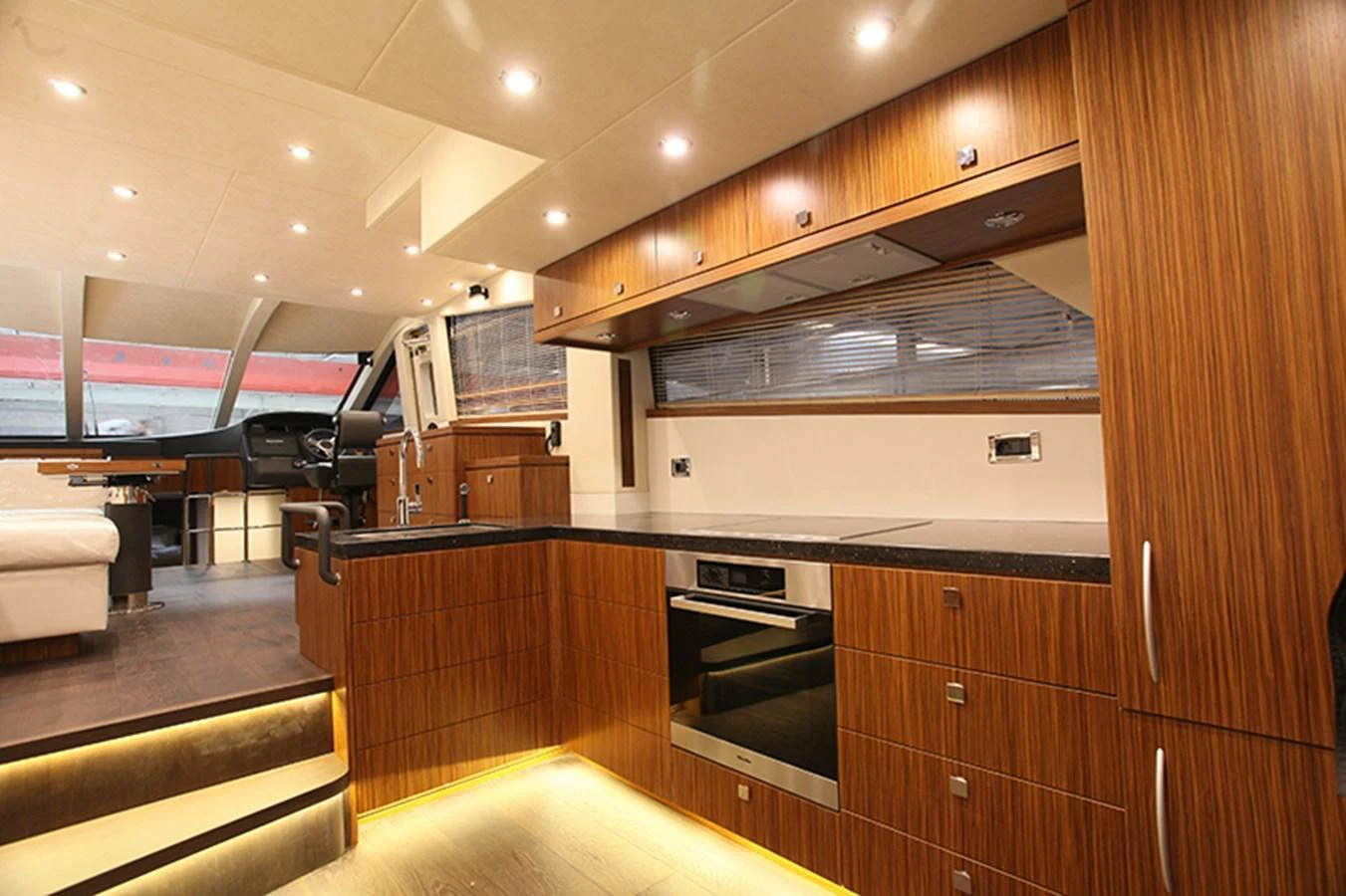 The yacht's galley features modern wood cabinetry, sleek appliances, and ambient lighting. aboard MAZARIN 72 FLYBRIDGE Yacht for Sale