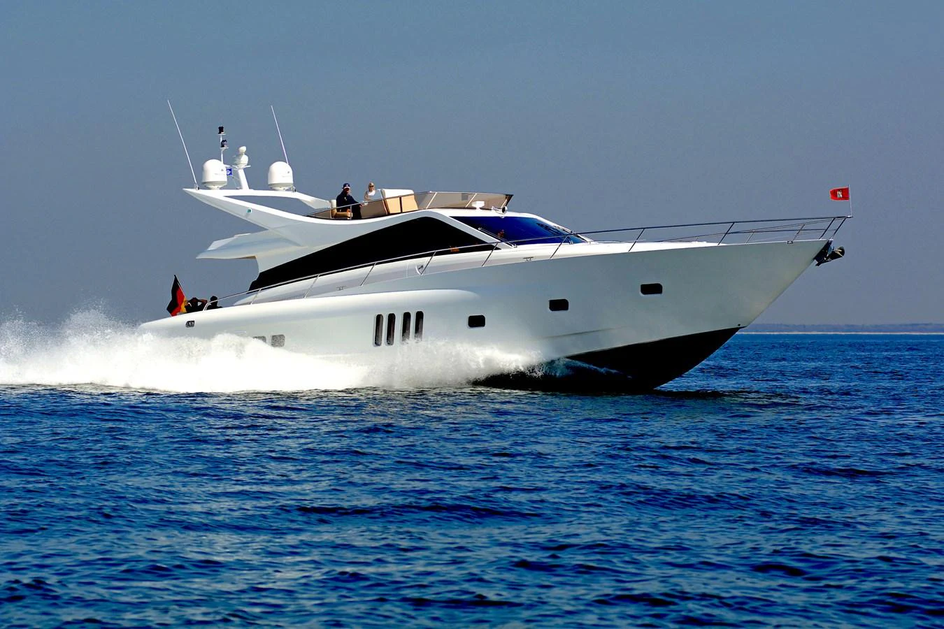 A sleek yacht cruises swiftly across the open water under a clear sky. aboard MAZARIN 72 FLYBRIDGE Yacht for Sale