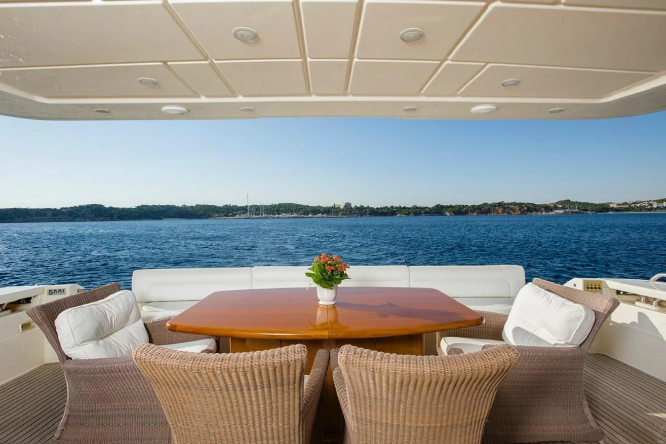 The aft deck features a stylish dining area with wicker chairs and a wooden table, offering a serene view of the water. aboard FERRETTI 881 Yacht for Sale