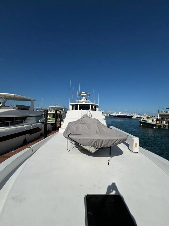 The yacht's bow is shown docked at a marina, with a covered tender on the deck and a clear blue sky overhead. aboard ADDISYN ANN Yacht for Sale