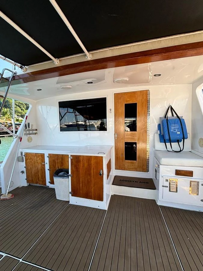 The aft deck features a clean and functional layout with wooden cabinetry and a door leading to the interior. aboard ADDISYN ANN Yacht for Sale