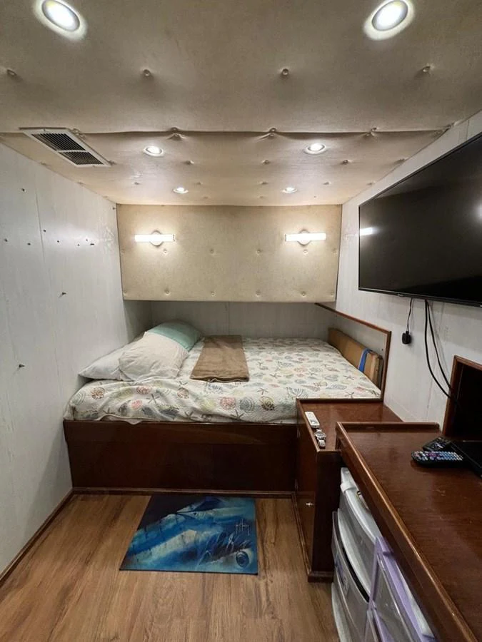 A cozy stateroom featuring a comfortable bed, wall-mounted TV, and wooden furnishings. aboard ADDISYN ANN Yacht for Sale