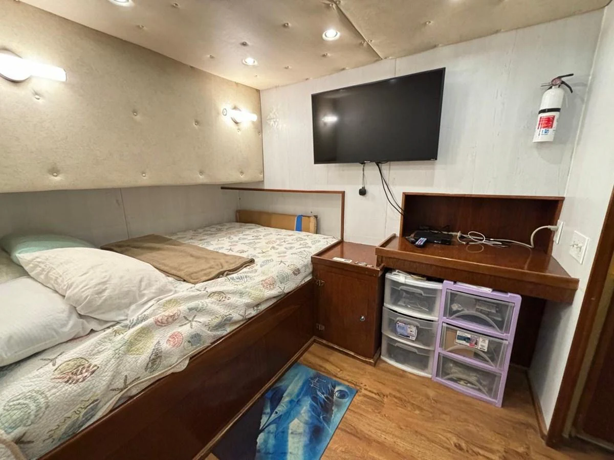 A cozy stateroom featuring a comfortable bed, a wall-mounted TV, and ample storage space. aboard ADDISYN ANN Yacht for Sale