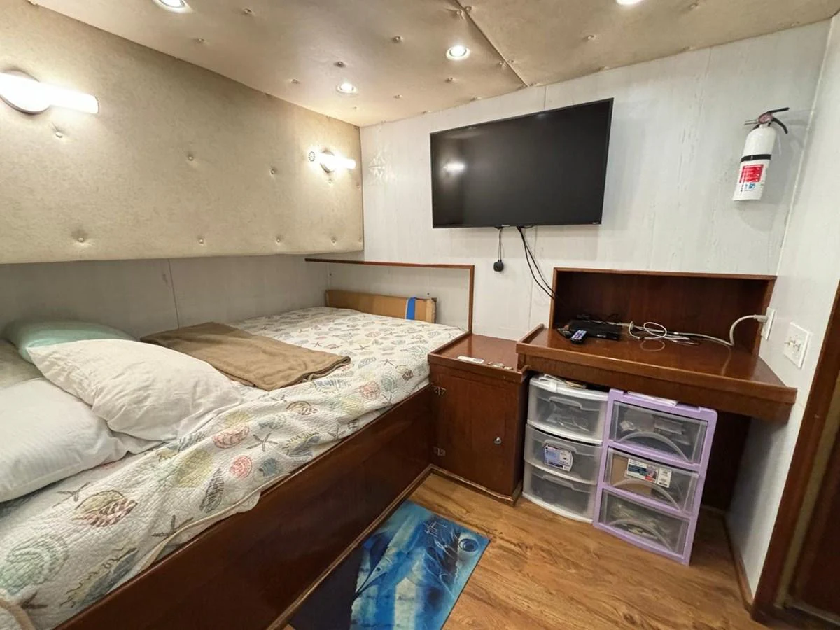 A cozy yacht cabin featuring a comfortable bed, a wall-mounted TV, and ample storage space. aboard ADDISYN ANN Yacht for Sale