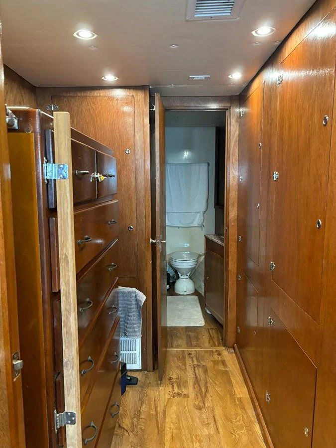 A warm, wood-paneled hallway leads to a bathroom, showcasing ample storage and elegant finishes. aboard ADDISYN ANN Yacht for Sale