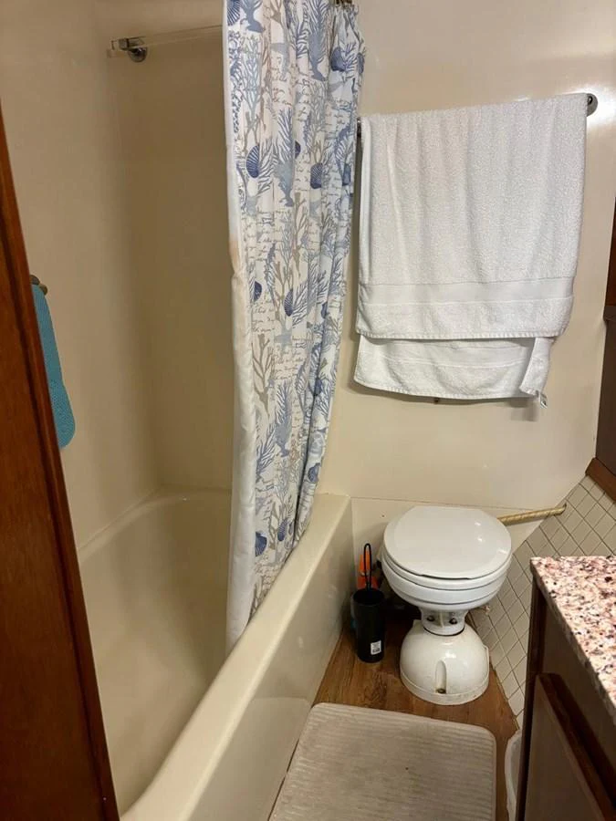 A cozy yacht bathroom featuring a shower with a patterned curtain, a toilet, and a towel rack. aboard ADDISYN ANN Yacht for Sale