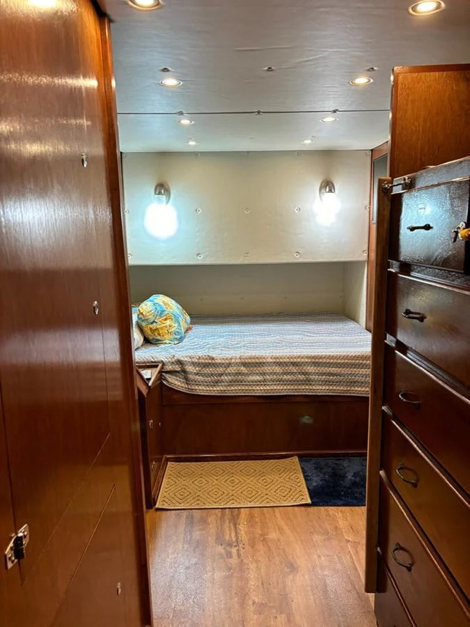 A cozy cabin with a single bed, wooden furnishings, and soft lighting. aboard ADDISYN ANN Yacht for Sale
