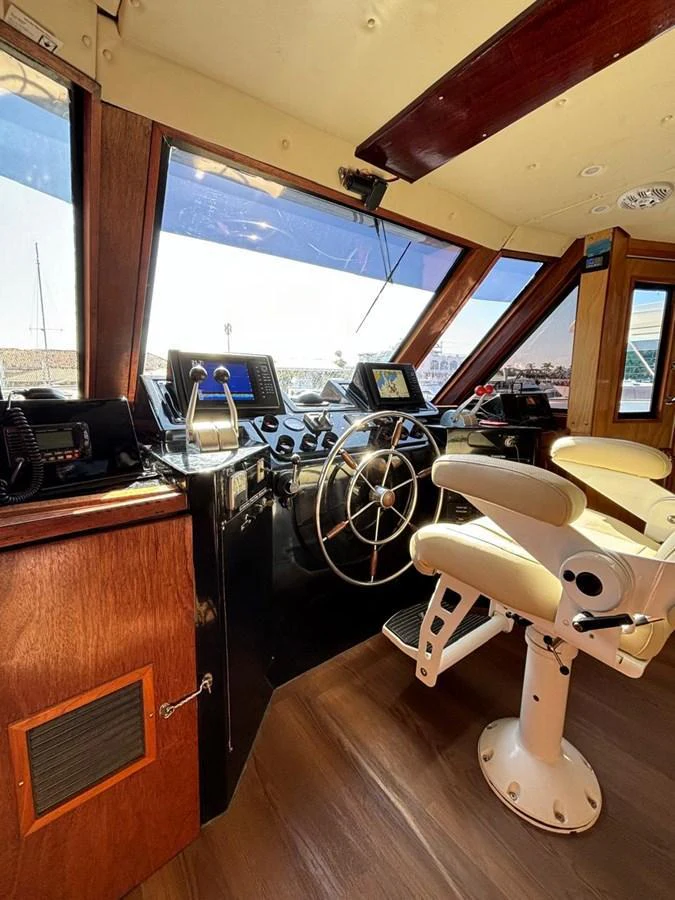 The helm station features a sophisticated steering wheel and advanced navigation equipment, offering a commanding view through large windows. aboard ADDISYN ANN Yacht for Sale