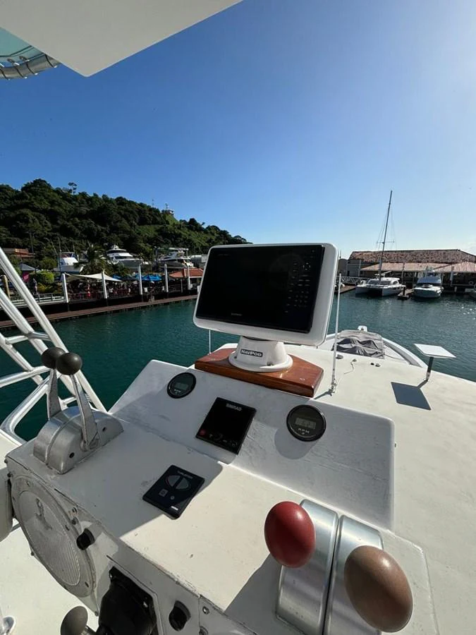 The helm station features modern navigation equipment with a scenic marina backdrop. aboard ADDISYN ANN Yacht for Sale