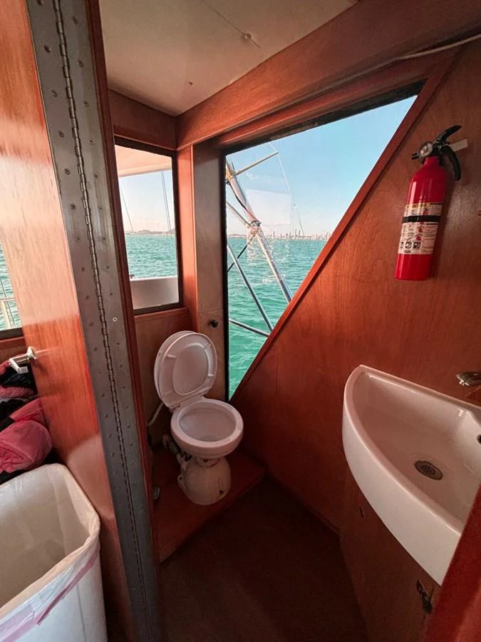 A compact yacht head with a toilet, sink, and a window offering a view of the sea. aboard ADDISYN ANN Yacht for Sale