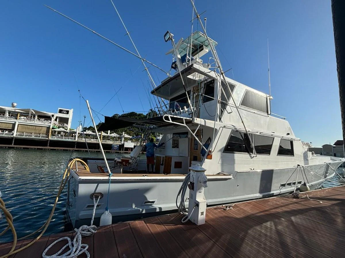 A sleek yacht is docked at a marina, showcasing its modern design and fishing equipment. aboard ADDISYN ANN Yacht for Sale