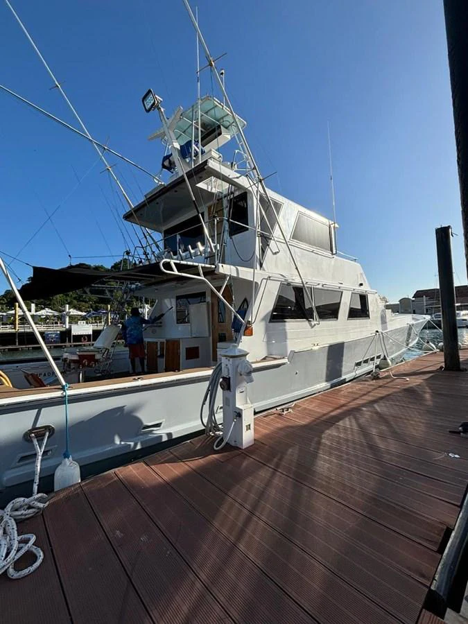 A well-maintained yacht docked at a marina, showcasing its multi-level structure and fishing equipment. aboard ADDISYN ANN Yacht for Sale