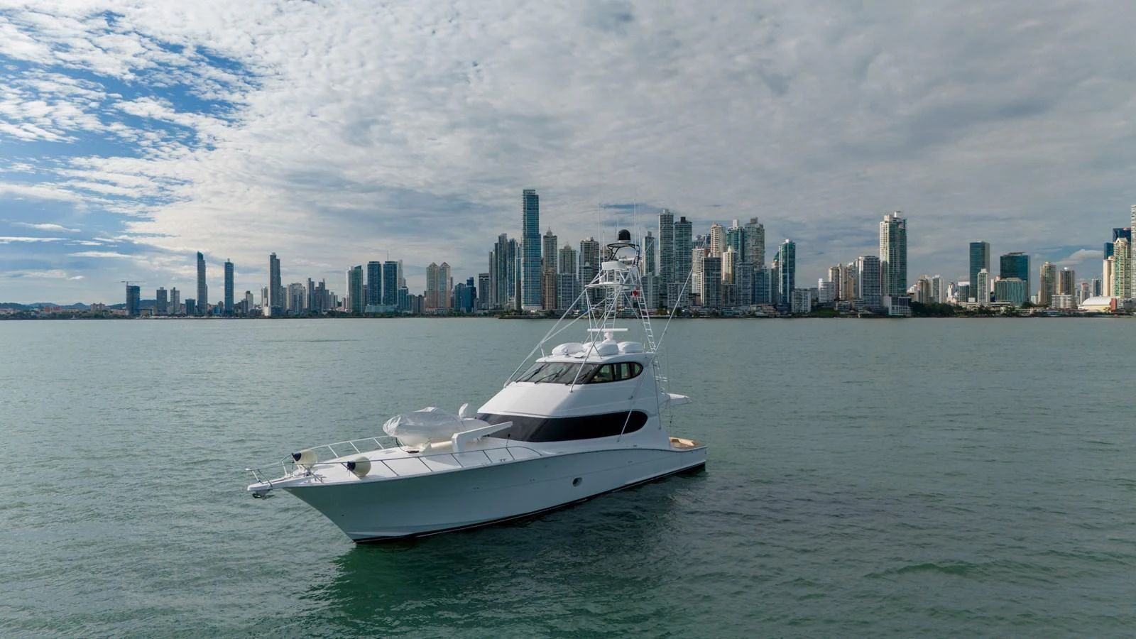 A sleek yacht cruises gracefully against a stunning city skyline backdrop. aboard VIDA 1 Yacht for Sale