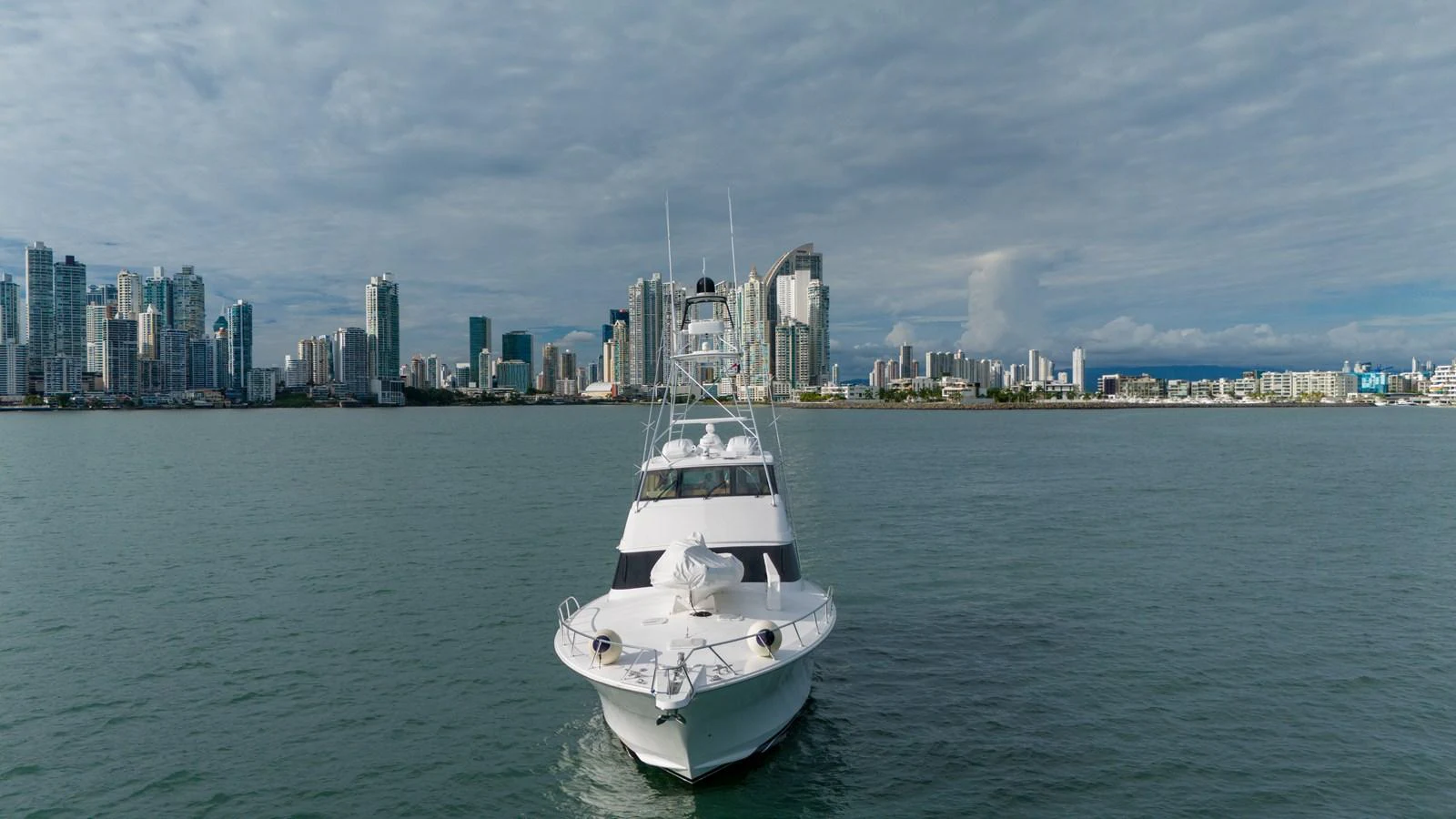 The yacht is cruising towards the city skyline, showcasing its sleek design against an urban backdrop. aboard VIDA 1 Yacht for Sale