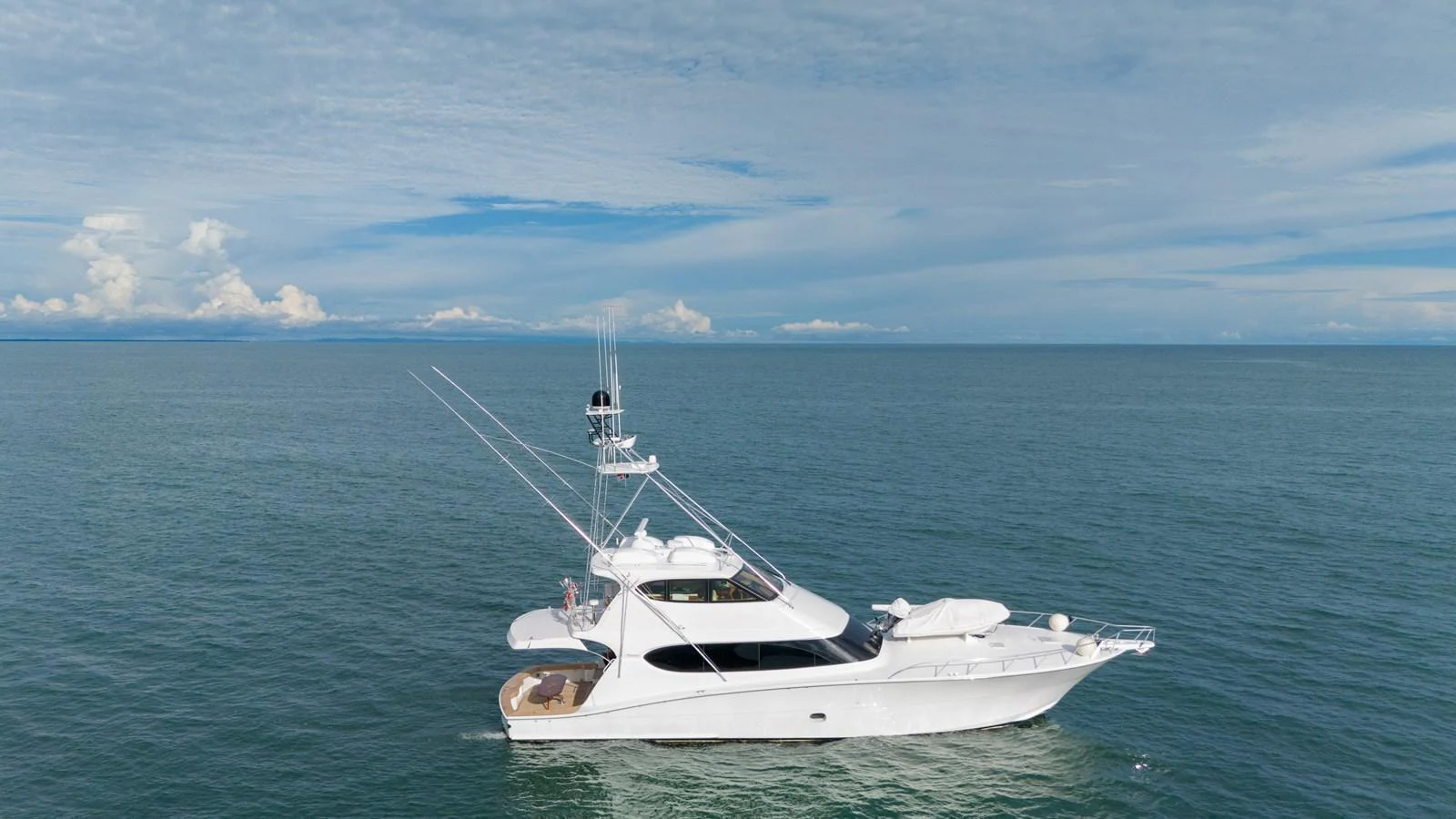 A sleek white yacht cruises on calm blue waters under a clear sky. aboard VIDA 1 Yacht for Sale