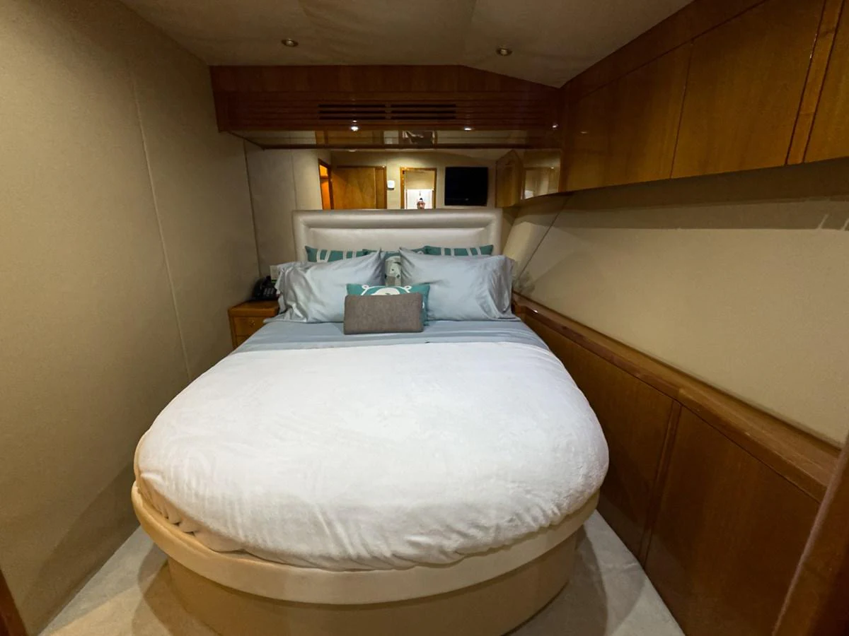 A cozy stateroom featuring a comfortable bed with plush pillows and wooden cabinetry. aboard VIDA 1 Yacht for Sale