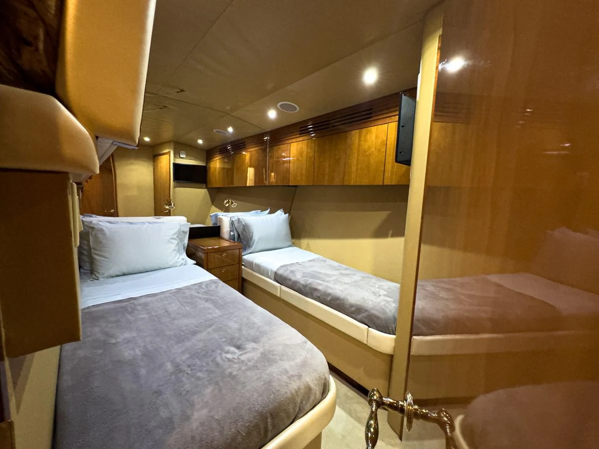 The cozy twin stateroom features two single beds with plush bedding and warm wooden accents. aboard VIDA 1 Yacht for Sale