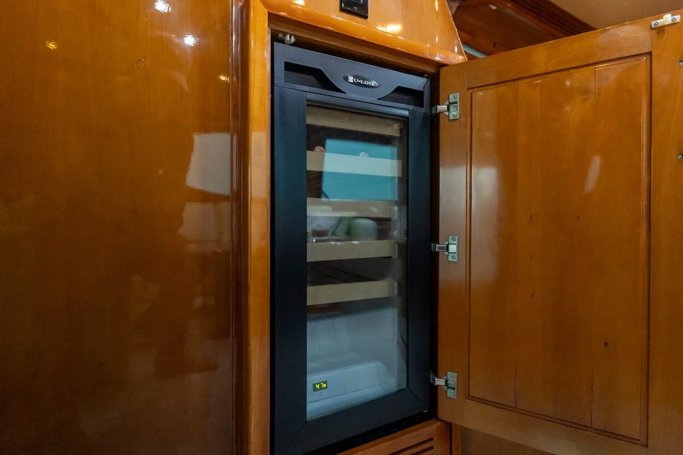 A close-up of a built-in wine cooler within a wooden cabinet on the yacht. aboard VIDA 1 Yacht for Sale