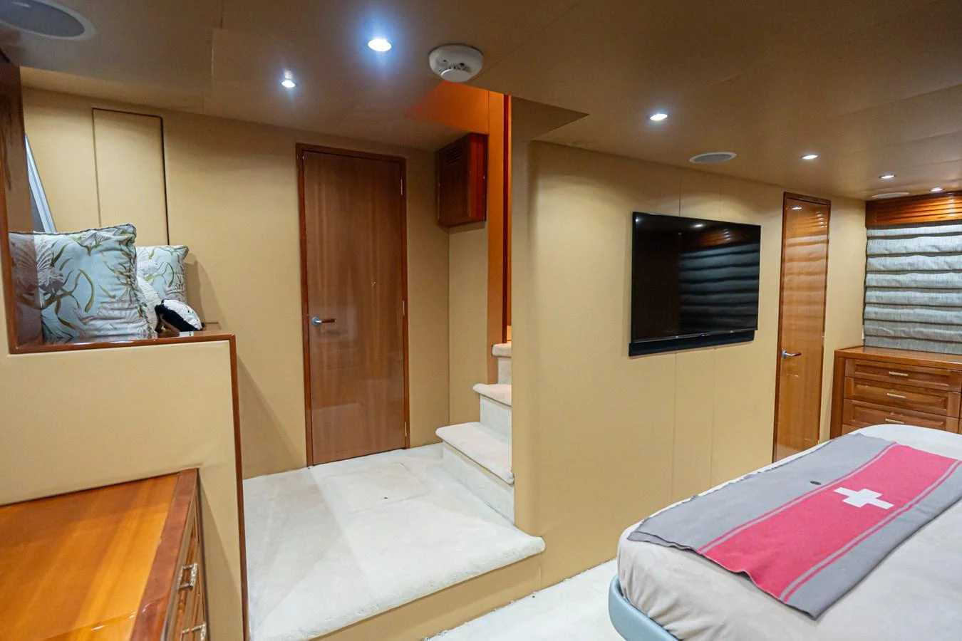 A cozy stateroom featuring a comfortable bed, a flat-screen TV, and a staircase leading to another level. aboard VIDA 1 Yacht for Sale