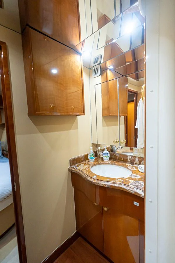 The yacht's bathroom features a polished wooden vanity with a marble countertop and mirrored cabinets. aboard VIDA 1 Yacht for Sale
